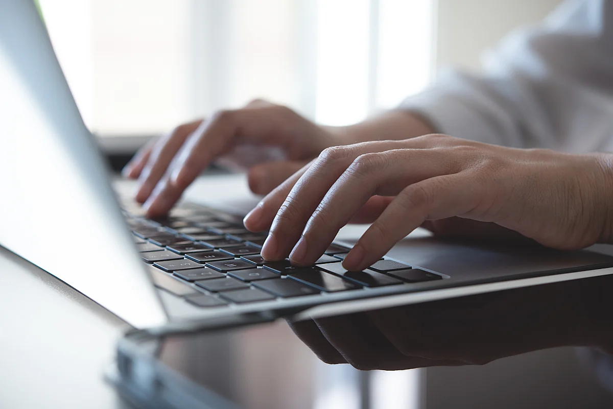 a close-up photo of somebody typing on laptop