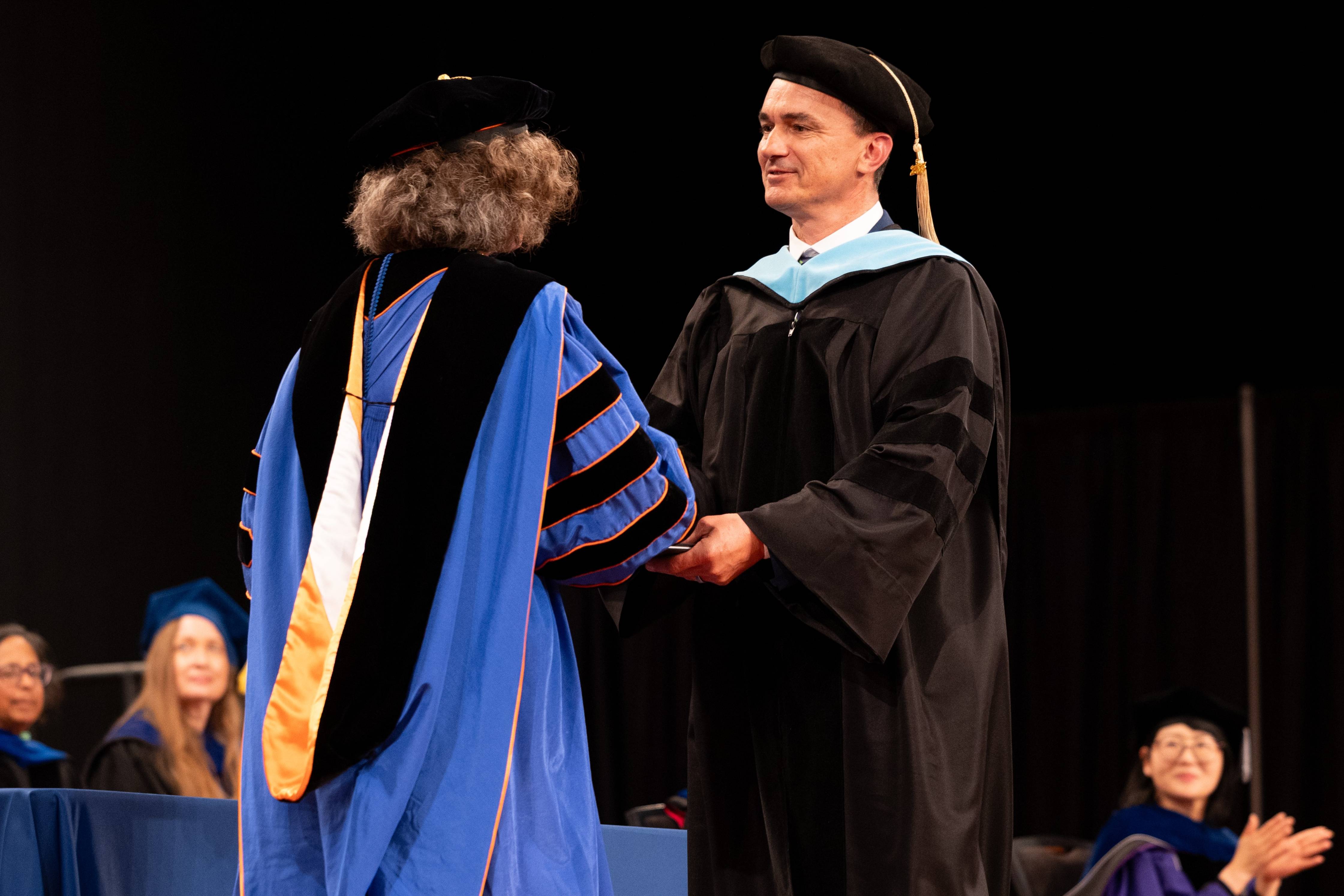 Student in doctoral regalia on stage.