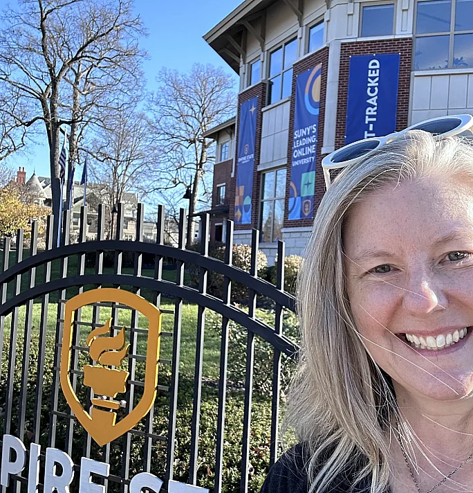 student takes photo of themselves in front Empire State University building