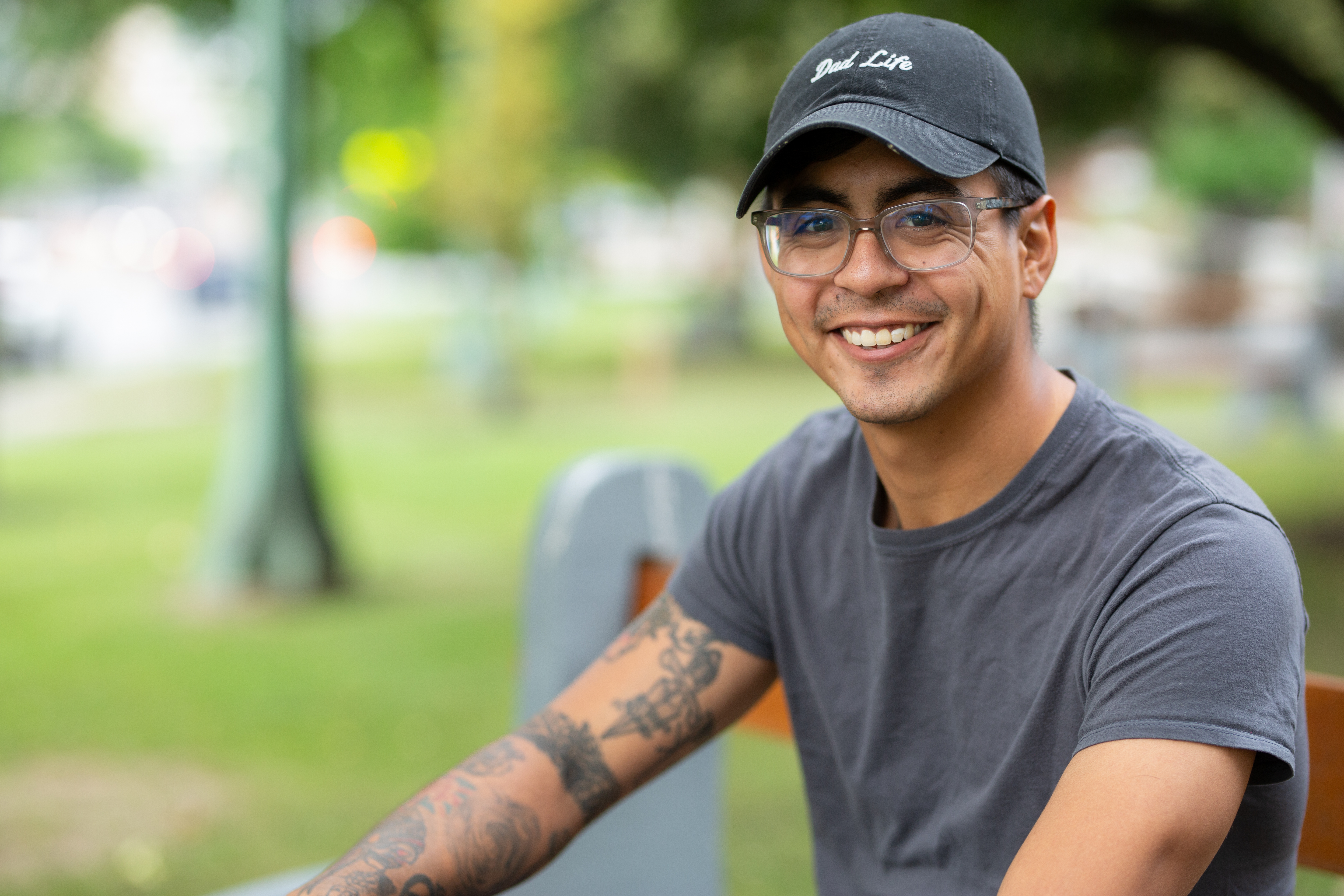 student sits on bench outside smiling