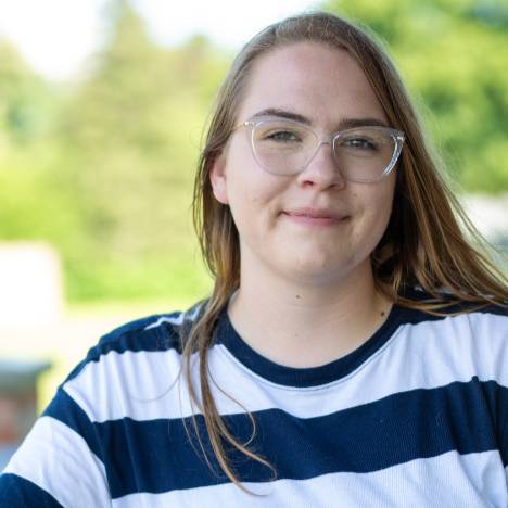 student smiles for a photo outside