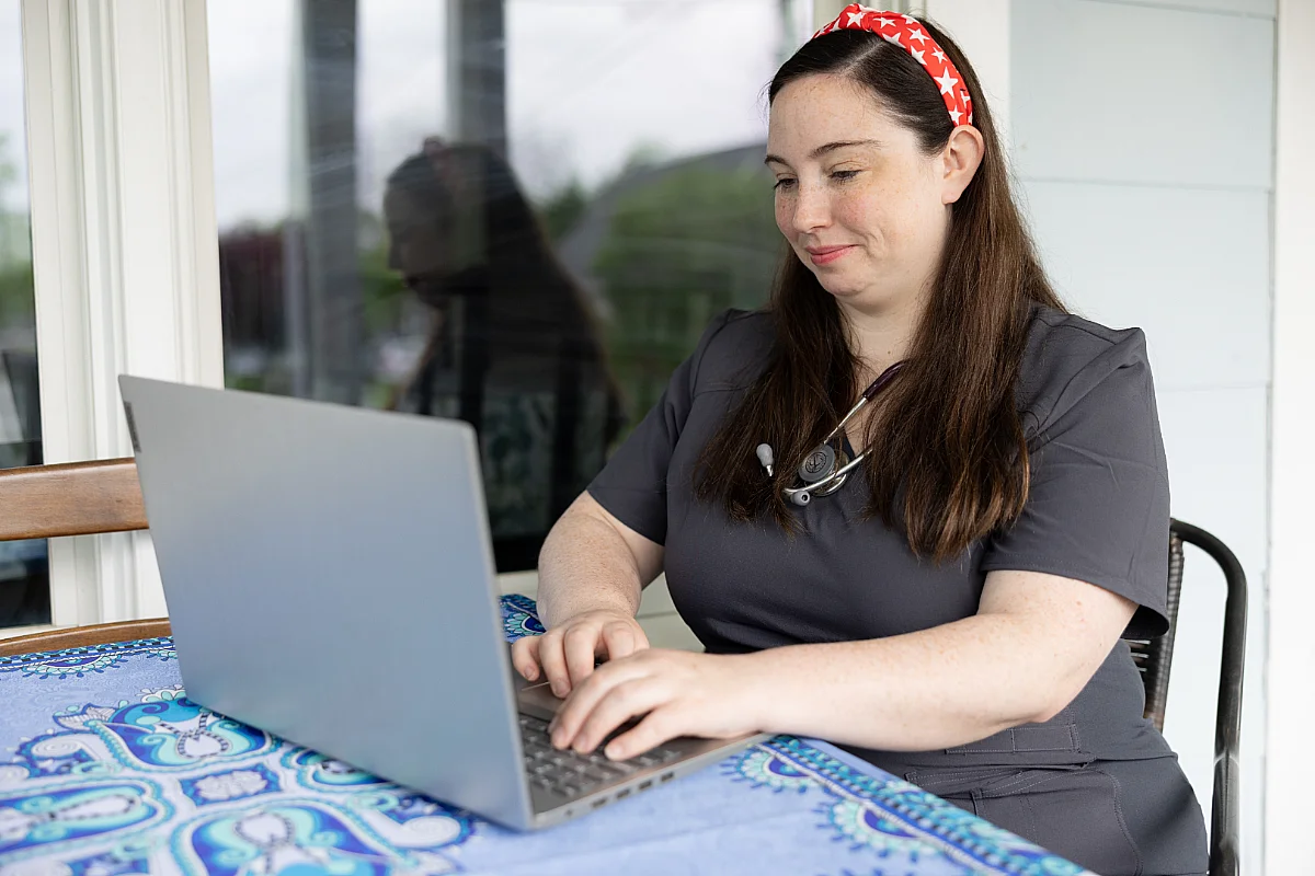 nursing student works on laptop in their home