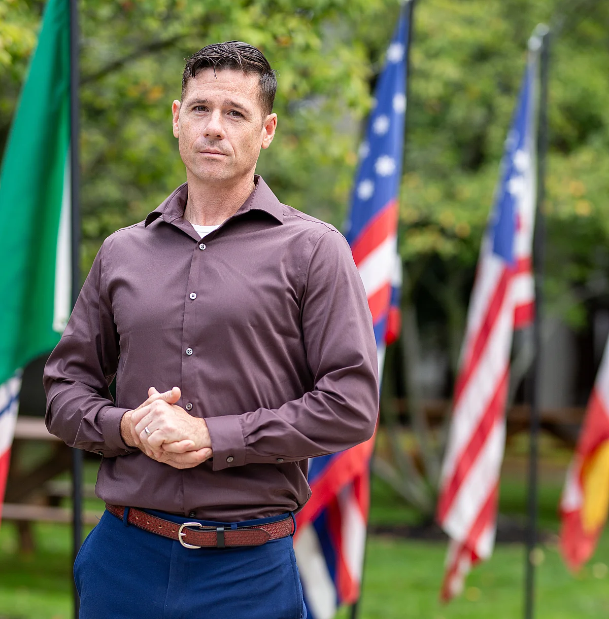student poses for photo in park in front of flags