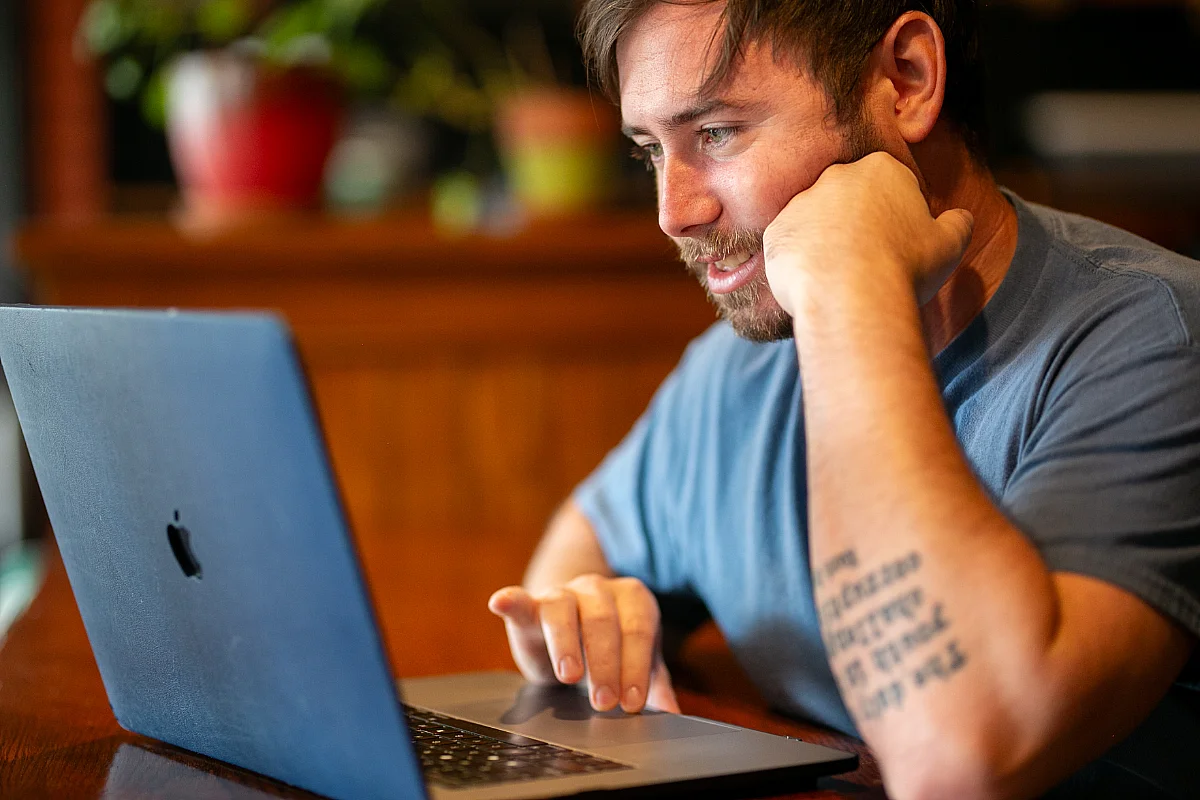 A man sits at a laptop.