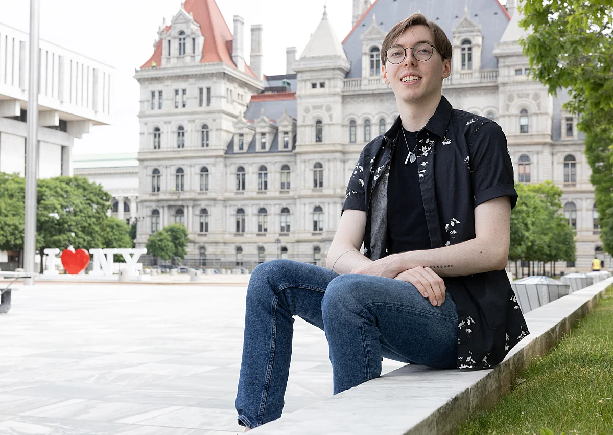 student smiles for photo with buildings in the background