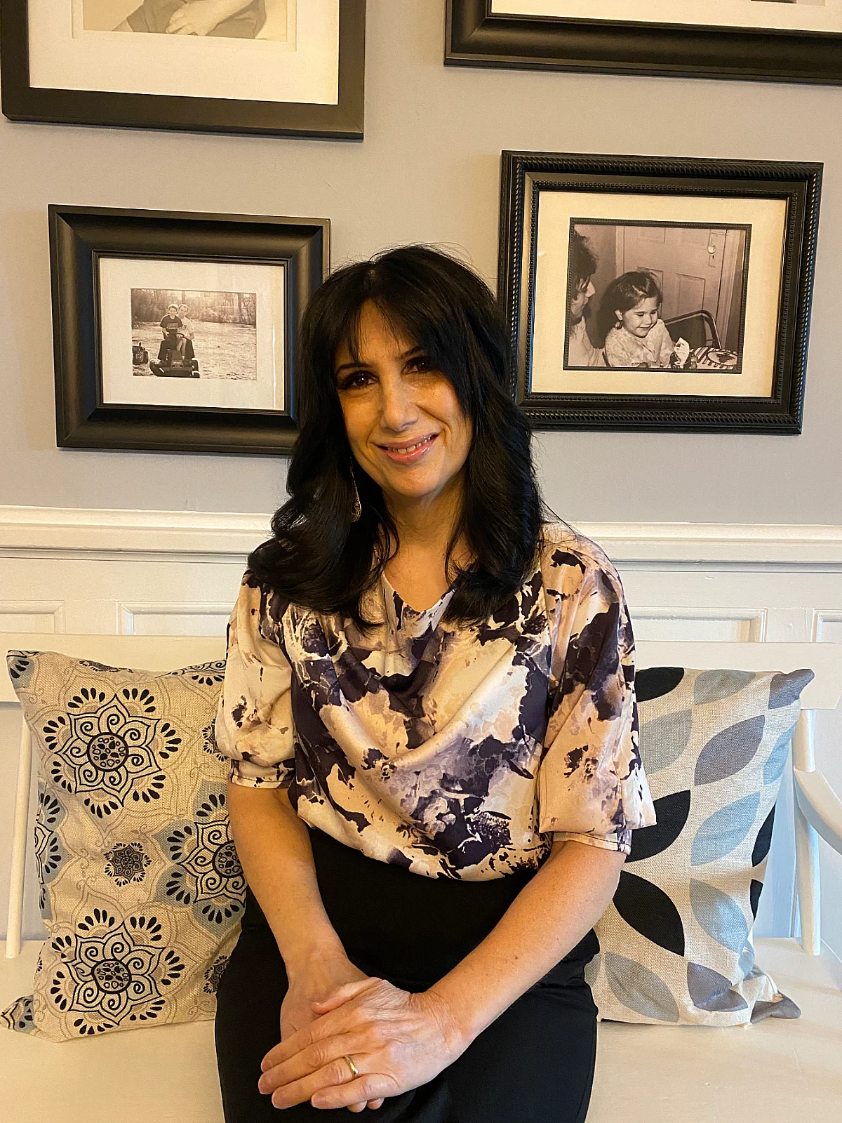 photo of student sitting in her home in front of frames on wall