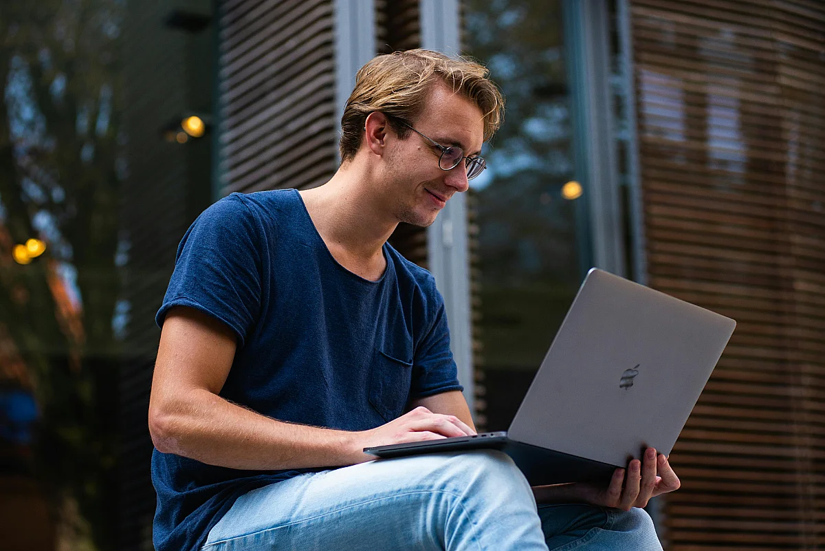 student sitting on steps working on his laptop