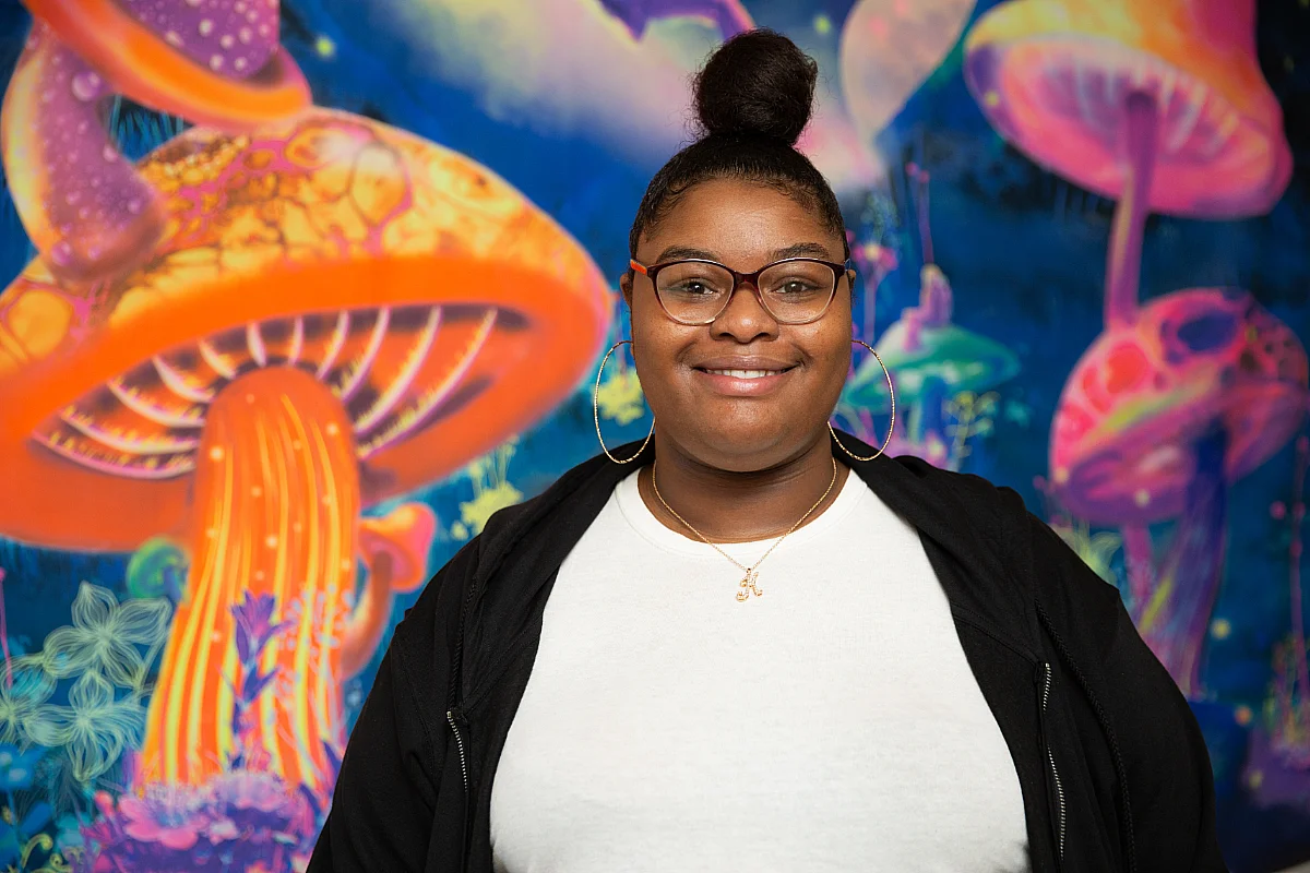 student stands in front of underwater tapestry