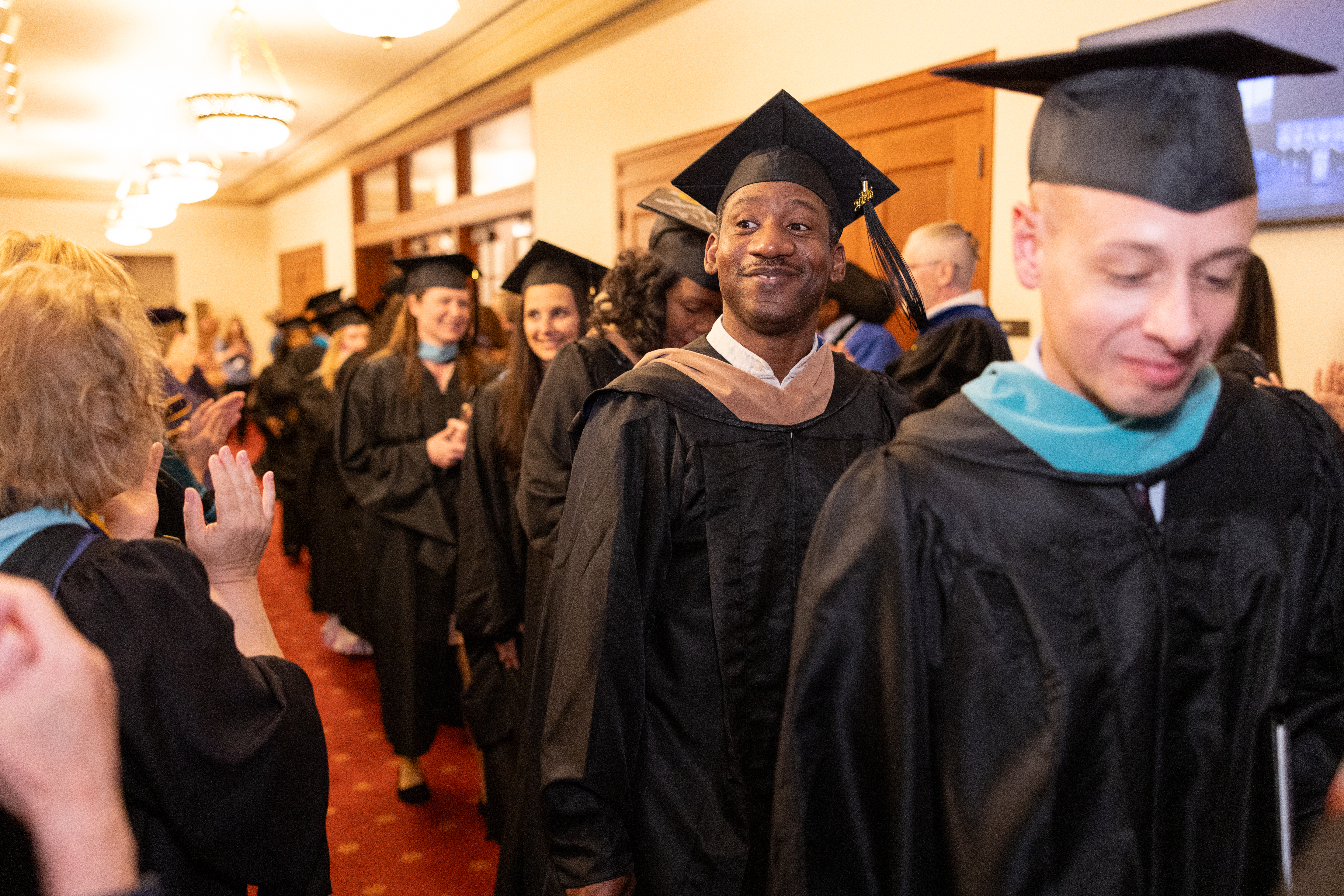 Students head toward the auditorium dressed in caps and gowns during the New York City commencement.