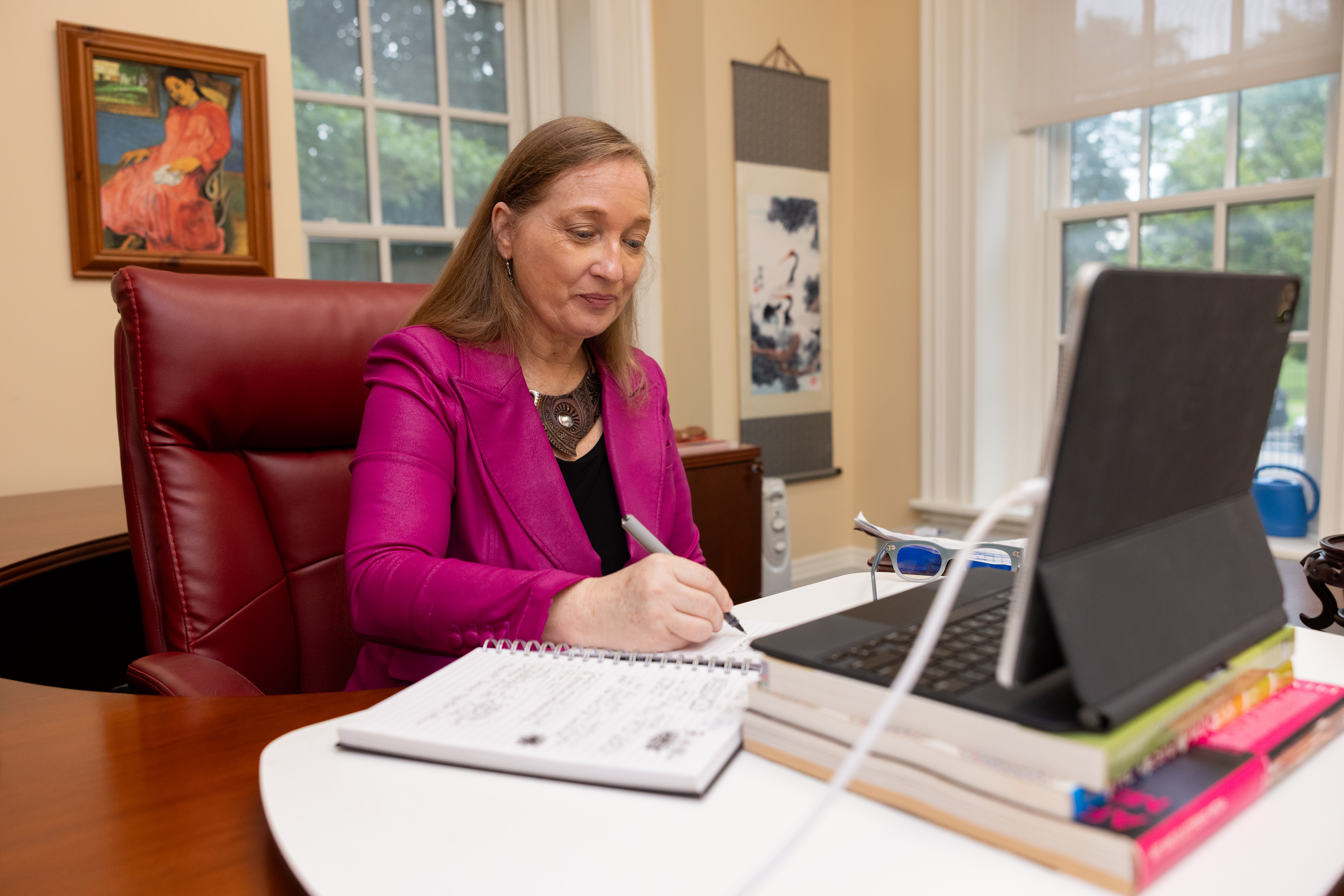 A woman works on a laptop while sitting at a desk.