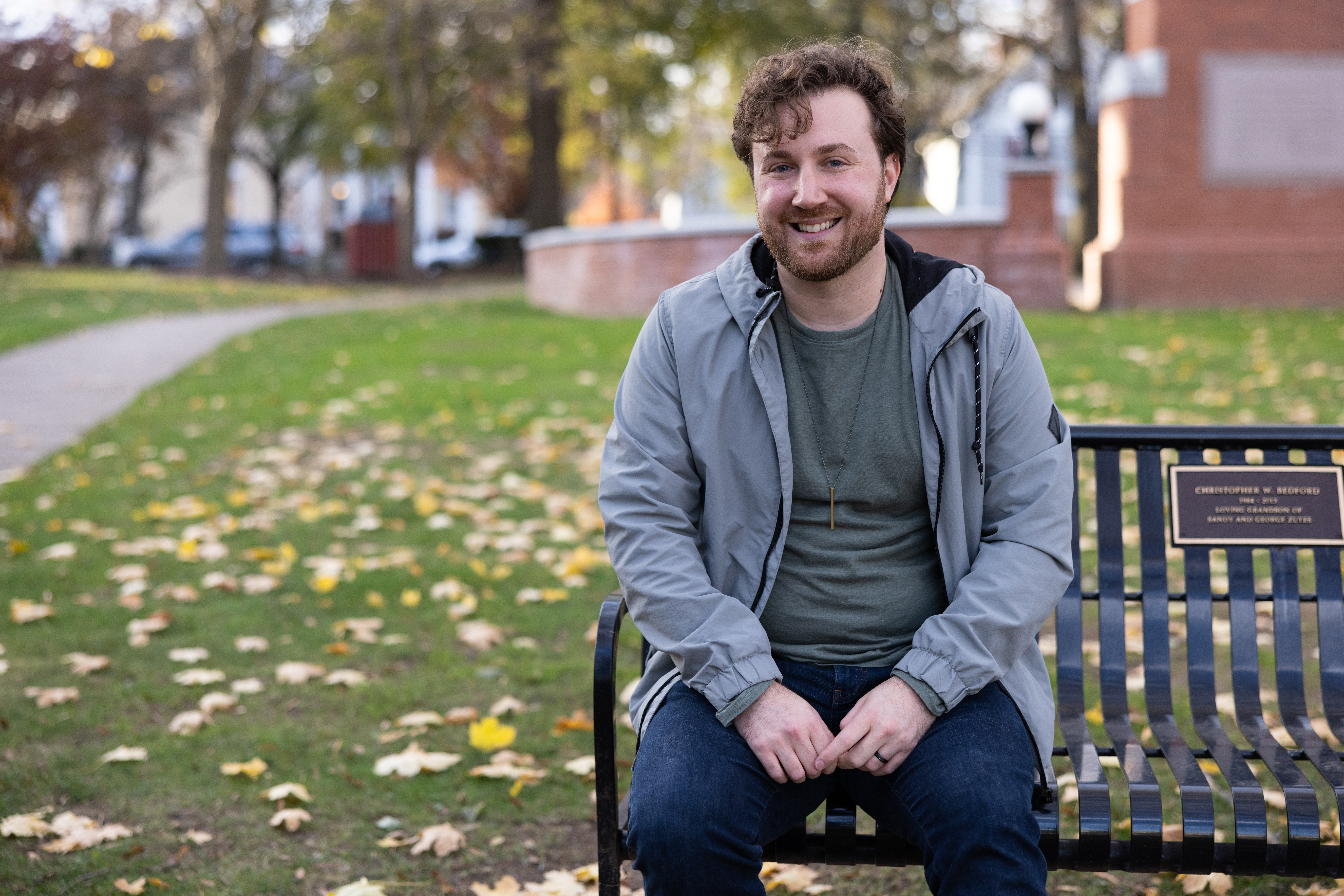 Male student sitting on a park bench.
