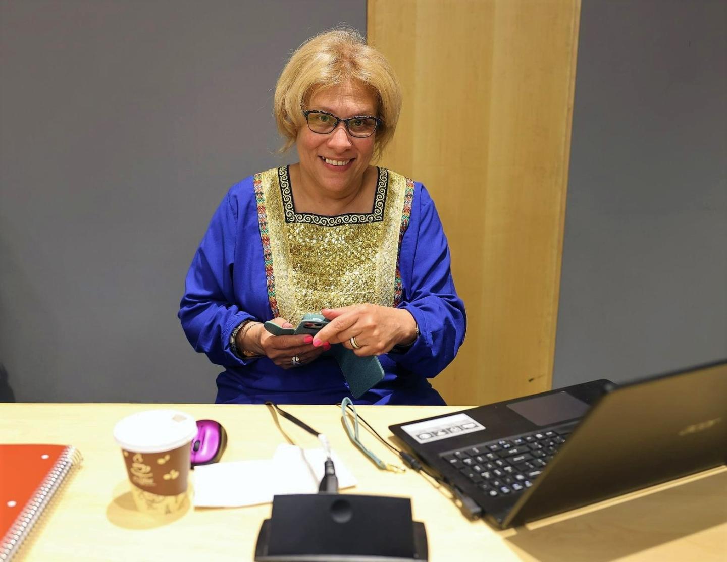 Image of Carmen Feliciano sitting at a desk with laptop for signing in students from the Black Male Initiative at SUNY Global.