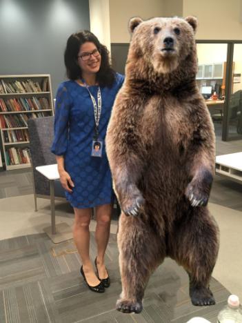 Photo of Samantha (in a blue dress) standing next to a bear.