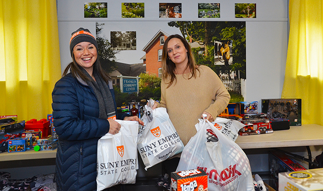 SUNY Empire employee Janet Aiello-Cerio, at left, drops off holiday gifts to Lindsay Duma, a volunteer with the Franklin Community Center.